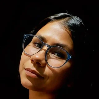 Retrato de Ambar Guevara, de Ambar Studio, con gafas y chaqueta oscura sobre fondo negro